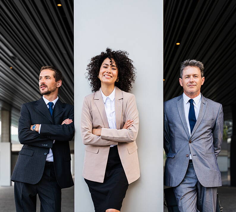 Drei Businesspersonen in Anzügen vor moderner Architektur – Symbol für selbstständige Versicherungsbroker und professionelle Zusammenarbeit im Netzwerk der Union Swiss Brokers Holding AG (USB) in der Schweiz.